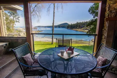 a glass table on a porch with a view of the water at Galiano Oceanfront Inn & Spa in Galiano