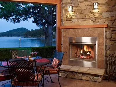 a fireplace on a patio with a table and chairs at Galiano Oceanfront Inn & Spa in Galiano