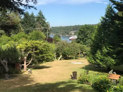 a park with a bench and trees and a body of water at Driftwood Village Cottages in Sturdies Bay