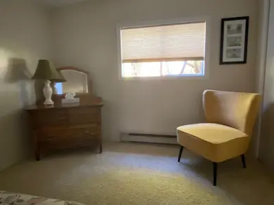 a room with a chair and a dresser and a window at Driftwood Village Cottages in Sturdies Bay