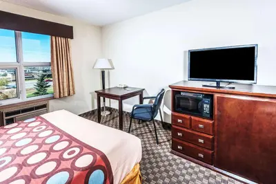 a hotel room with a bed and a flat screen tv at Super 8 by Wyndham Calgary/Airport in Calgary