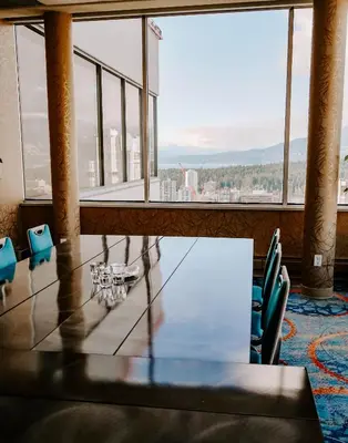 a table and chairs in a room with a large window at Blue Horizon Hotel in Vancouver