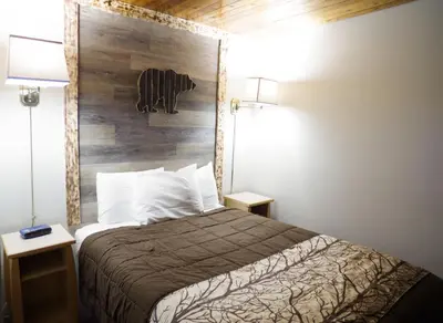 a bedroom with a bed with a wooden wall at Canadas Best Value Inn and Suites Fernie in Fernie