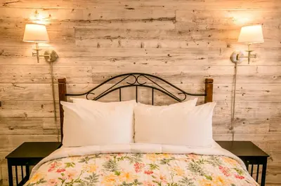 a bed with two lamps on a wooden wall at Inn on Canyon in Radium Hot Springs