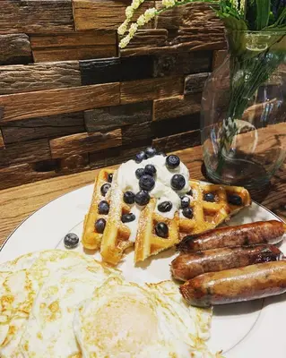 a white plate with waffles and sausage on a table at Inn on Canyon in Radium Hot Springs