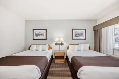 a hotel room with two beds and a window at Canmore Rocky Mountain Inn in Canmore