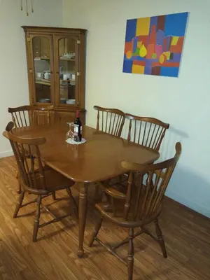 a wooden table with four chairs and a bottle of wine at Rosedale Manor in Duncan