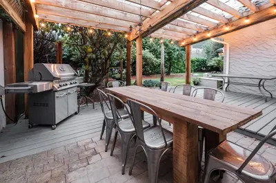 a wooden table and chairs on a deck with a grill at Bramblebank Cottages in Harrison Hot Springs