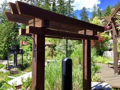 a wooden pergola in the middle of a garden at The Tuwanek Bed and Breakfast in Sechelt