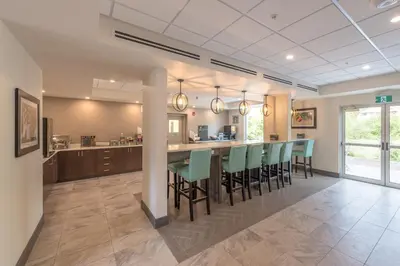 a kitchen and dining room with a bar with green chairs at Coast Oliver Hotel in Oliver