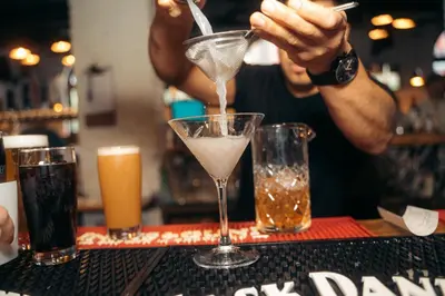 a bartender is mixing a drink in a martini glass at The Cambie Hostel Seymour in Vancouver
