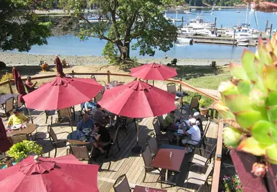 a group of people sitting on a deck with red umbrellas at Heriot Bay Inn in Heriot Bay