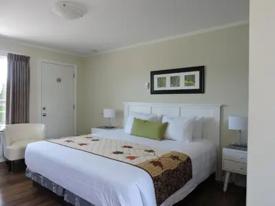 a bedroom with a large white bed and a chair at Almo Court Motel in Cranbrook