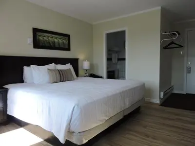 a bedroom with a large bed with white sheets at Almo Court Motel in Cranbrook