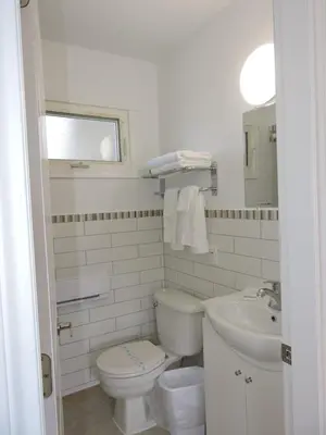 a white bathroom with a toilet and a sink at Almo Court Motel in Cranbrook