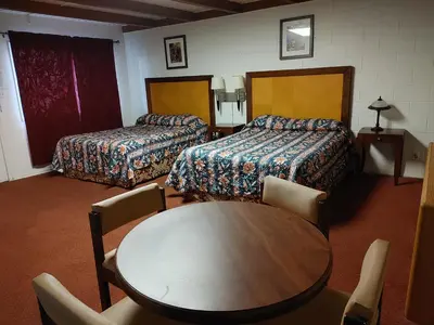 a hotel room with two beds and a table and chairs at Kootenay Country Inn in Cranbrook