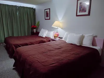 a hotel room with two beds with red sheets at Kootenay Country Inn in Cranbrook