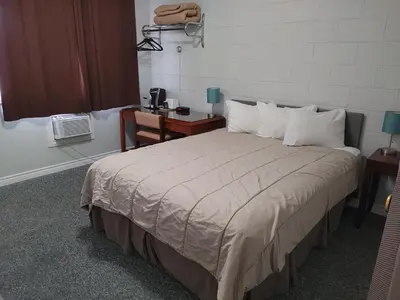 a bedroom with a large bed with a desk and a chair at Kootenay Country Inn in Cranbrook