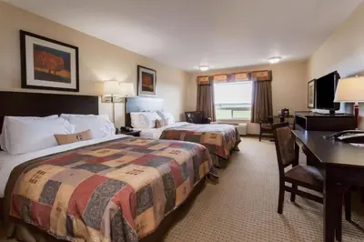 a hotel room with two beds and a desk at Ramada by Wyndham Westlock in Westlock