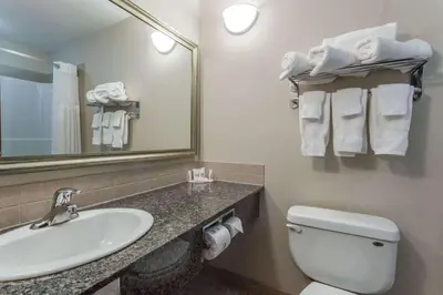 a bathroom with a sink and a toilet and a mirror at Ramada by Wyndham Westlock in Westlock
