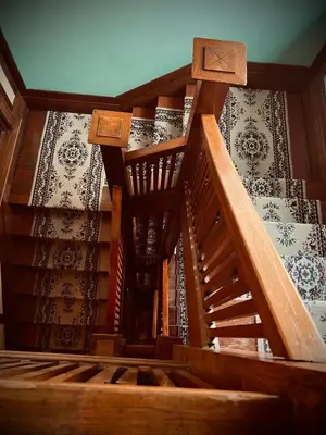 a wooden staircase in a room with wallpaper at Arundel Mansions Hotel in New Westminster