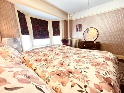 a bedroom with a bed with a floral bedspread at Arundel Mansions Hotel in New Westminster