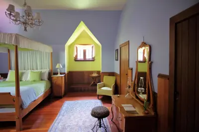 a bedroom with a bed and a table and a chair at Wedgwood Manor and Glamping Retreat in Crawford Bay