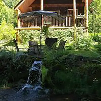 a pond with chairs and an umbrella in front of a house at Wedgwood Manor and Glamping Retreat in Crawford Bay