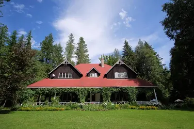 a house with a red roof on a green field at Wedgwood Manor and Glamping Retreat in Crawford Bay