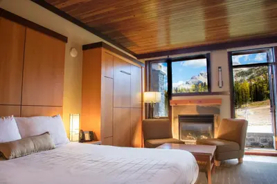 a bedroom with a large bed and a fireplace at Sunshine Mountain Lodge in Banff