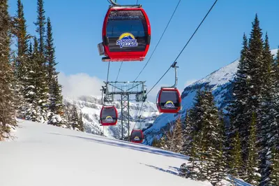 a group of ski lifts flying over a snow covered mountain at Sunshine Mountain Lodge in Banff