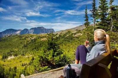 a woman sitting on a bench looking at the mountains at Sunshine Mountain Lodge in Banff