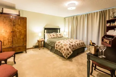 a bedroom with a bed and a dresser in a room at Rustlers Lodge in Sundre