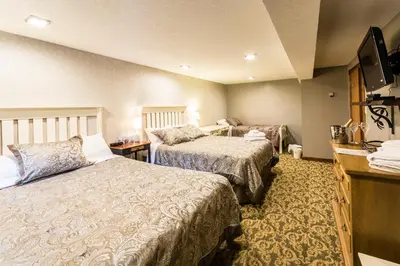 a hotel room with two beds and a television at Rustlers Lodge in Sundre