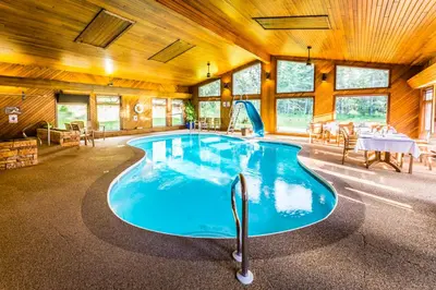 a large pool in a building with a table and chairs at Rustlers Lodge in Sundre