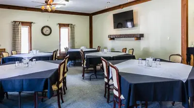 a room with tables and chairs and a clock on the wall at Rustlers Lodge in Sundre