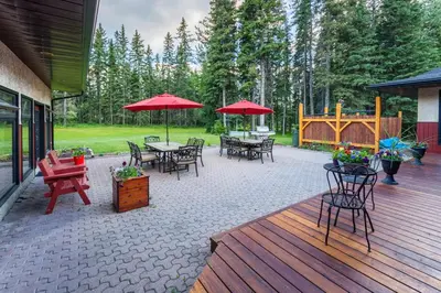 a patio with tables and chairs and red umbrellas at Rustlers Lodge in Sundre