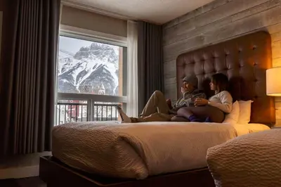 two people sitting on a bed in a hotel room at Lamphouse By Basecamp in Canmore