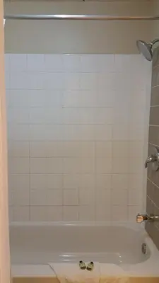 a bathroom with a tub and a tiled wall at Chinook Country Inn in Sundre