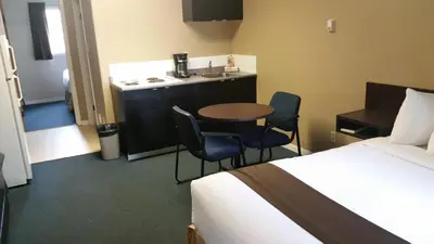 a hotel room with a bed and a table and chairs at Chinook Country Inn in Sundre