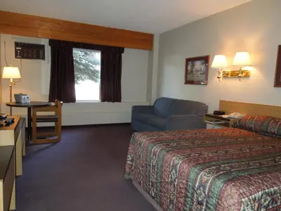 a hotel room with a bed and a chair at Walking Eagle Inn & Lodge in Rocky Mountain House