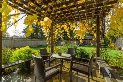 a patio with a table and chairs under a pergola at Imperial House in Burnaby