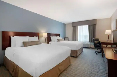 a hotel room with two beds and a desk at Best Western Rocky Mountain House Inn & Suites in Rocky Mountain House