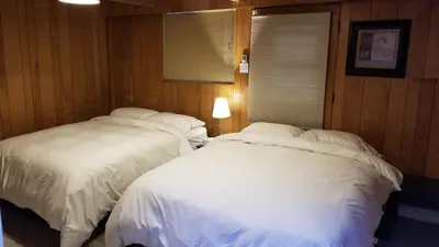 two white beds in a room with wood walls at City Gardens Suites B&B in North Vancouver