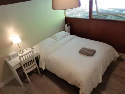 a bedroom with a white bed with a chair and a table at City Gardens Suites B&B in North Vancouver