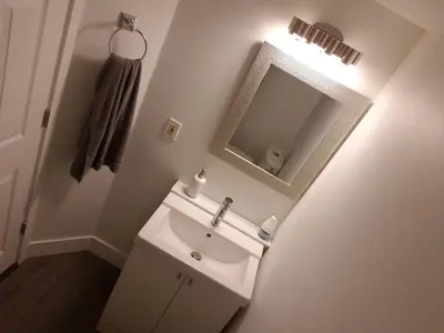 a white bathroom with a sink and a mirror at City Gardens Suites B&B in North Vancouver