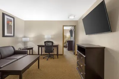 a hotel room with a couch and a desk and a television at Best Western Bonnyville Inn & Suites in Bonnyville