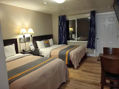 a hotel room with two beds and a desk at Harbour Light Motel in Nanaimo