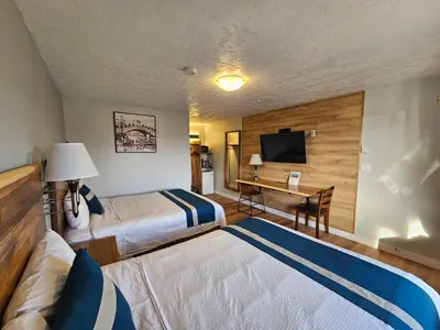 a hotel room with two beds and a desk at Harbour Light Motel in Nanaimo