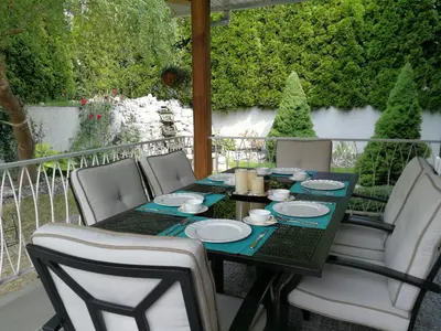 a table and chairs on a porch with a table and plates at Casa Grande Lakeview House in West Kelowna